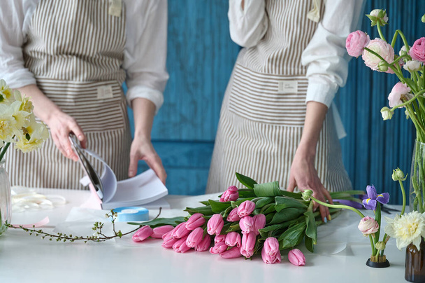 Teamwork. Two young beautiful florists create a bouquet - Foto, afbeelding