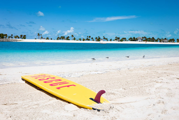 A surf board with stamped text saying rescue on a beach of a tropical island lagoon - Photo, Image