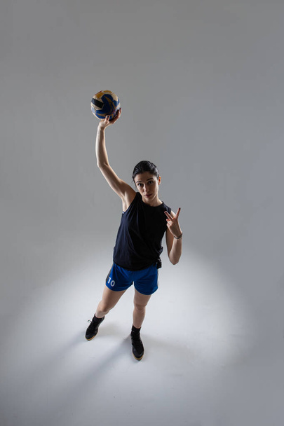 Handball player posing on light gray background. Girl posing with ball. - Фото, изображение