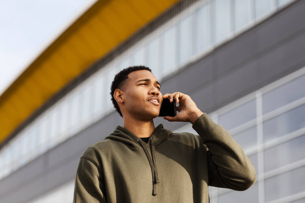 young african american man in casual outfit standing and talking on phone - Zdjęcie, obraz