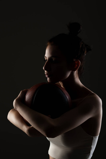 Teenage girl with basketball. Side lit studio portrait against dark background. - Fotoğraf, Görsel