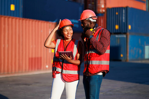 Portriat handsome male African American Industrial and female cock warehouse specialist. Black man worker wearing yellow protective hard hat helmet working at container yard. - Foto, immagini