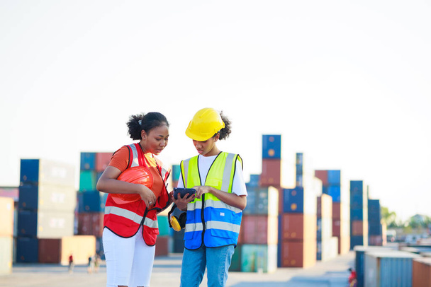 Two friends Black female dock worker relax talking in break time at warehouse container yard. Marine and carrier insurance concept. logistic shipping yard - Photo, image
