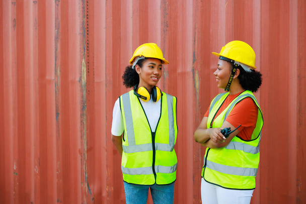 Two friends Black female dock worker relax talking in break time at warehouse container yard. Marine and carrier insurance concept. logistic shipping yard - Foto, immagini