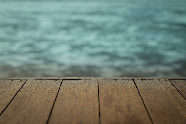 Drewniana podłoga rozciąga się do morza, gdy woda spada z zachodu słońca tle - Zdjęcie, obraz