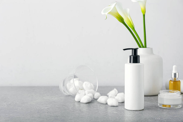 Cosmetic products, cotton balls and calla lilies on table - Fotoğraf, Görsel