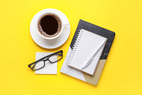 Composition with cup of coffee, notebooks and eyeglasses on color background - Photo, image