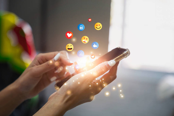 Young woman using smartphone sending emojis. Mobile smartphone sending text messages emoji emoticon. - Foto, immagini