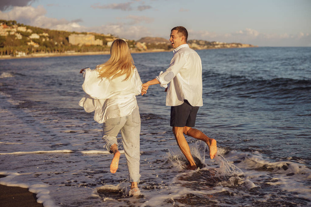 Обратный вид на мужчину и женщину, бегущих вдоль океана - Фото, изображение