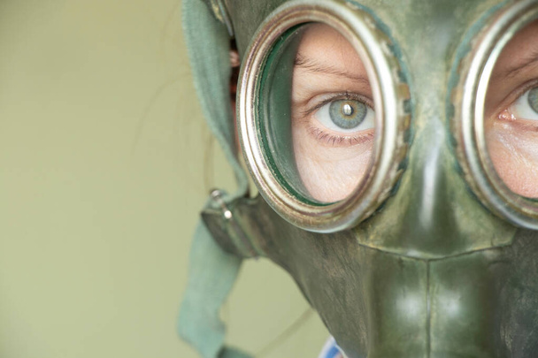 The face of a girl in a Soviet green gas mask on a green background, gas mask, gas attack, vintage gas mask - Foto, Imagen