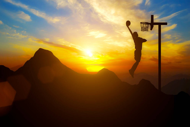 Ein Mann platziert ein Basketballtor auf einem Berg mit Sonnenuntergang - Foto, Bild