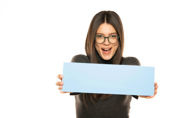 Schöne Frau hält eine leere blaue Plakatwand isoliert auf weißem Hintergrund - Foto, Bild