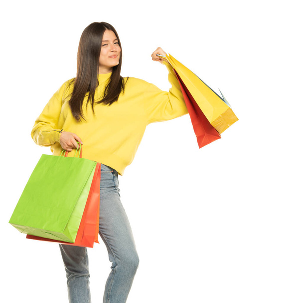 Portrait of a smiling beautiful woman wearing blouse and jeans holding shopping bags isolated over white background - Fotoğraf, Görsel