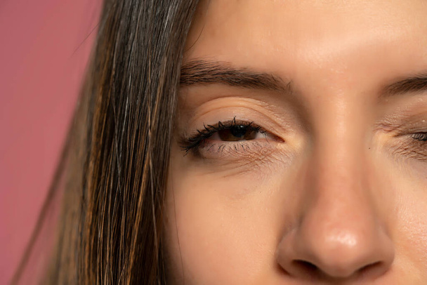 Cropped image of a woman with a half-closed eye. - Zdjęcie, obraz