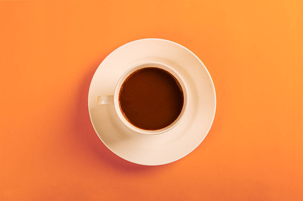 Black coffee in white ceramic cup on orange background - Фото, зображення