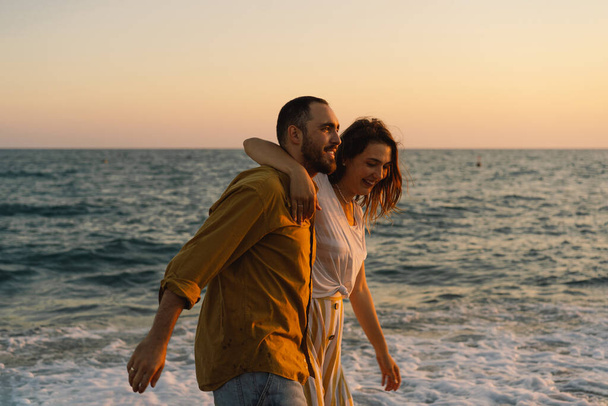 Νεαρό ρομαντικό ζευγάρι που χορεύει στη θάλασσα. Θαλάσσιο τοπίο στο ηλιοβασίλεμα με όμορφο ουρανό - Φωτογραφία, εικόνα