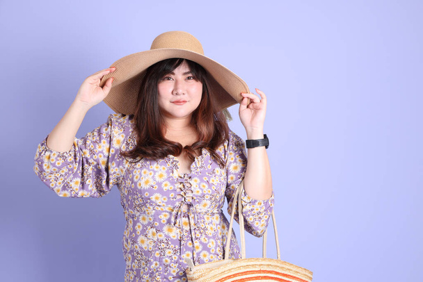 Толстая азиатка, стоящая на фиолетовом фоне в повседневной одежде. - Фото, изображение