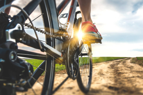 Foot on bike pedal at sunset. Close up rear view cyclist pedalling. Bicycle on the road. - Fotoğraf, Görsel