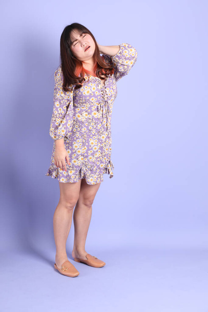 The chubby Asian woman standing on the purple background with the casual clothes. - Photo, image