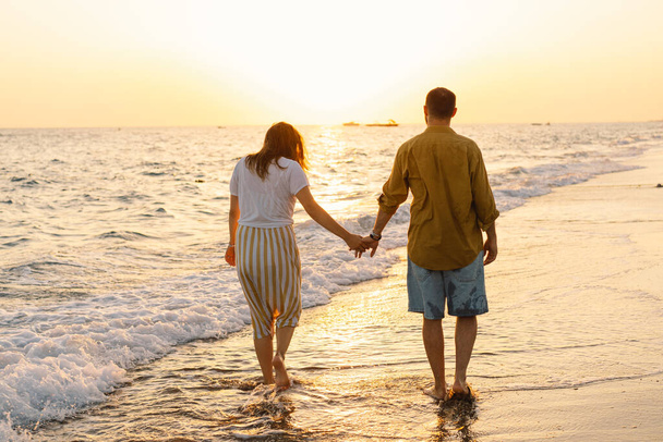 Fiatal romantikus pár táncol a tengeren. Napnyugtakor gyönyörű égbolttal - Fotó, kép