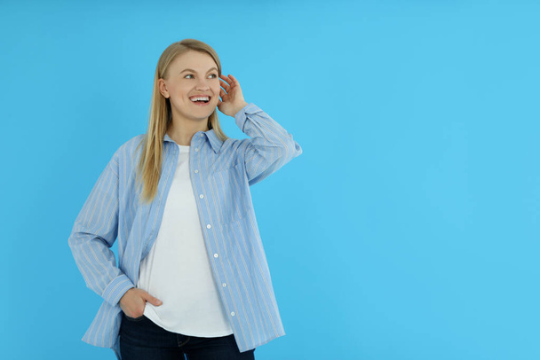 Young woman on blue background, space for text - Foto, afbeelding