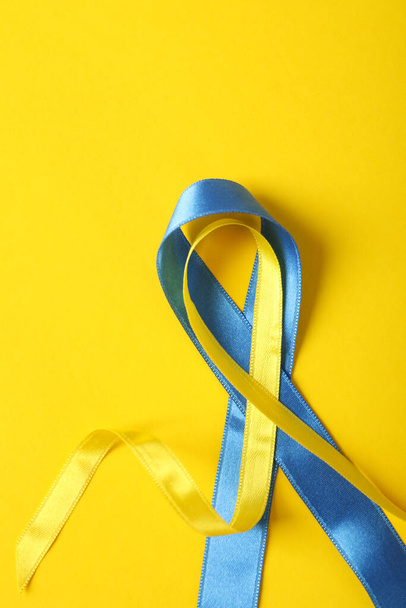 Υποστήριξη της Ουκρανίας έννοια, μπλε και κίτρινες κορδέλες ευαισθητοποίησης σε κίτρινο φόντο - Φωτογραφία, εικόνα