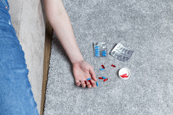 pill danger concept. the man was poisoned by pills. An arm dangled from the couch and pills were scattered on the floor. - Foto, Imagem
