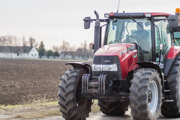 Нови-Сад, Сербия - 05 марта. 2021: Красный сельскохозяйственный трактор едет по шоссе. - Фото, изображение