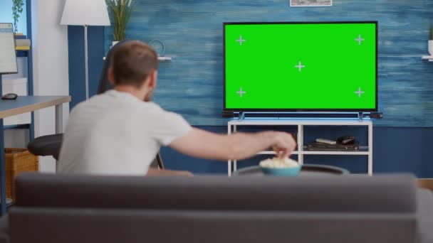 Sport fan sitting on sofa watching sport game on green screen tv mockup encouraging favourite team - Кадры, видео