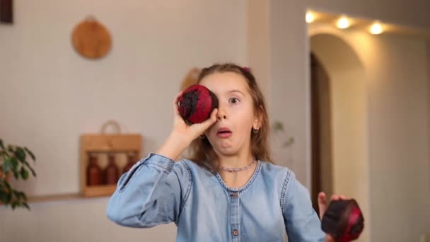 Happy emotional little girl holding cupcakes in hands covering eyes at home, smiling happy children loving sweet concept and sugar nutrition - Záběry, video