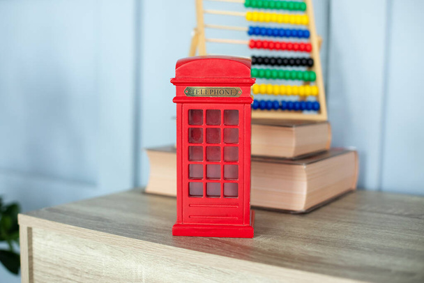 Figurine of a red telephone booth on shelf. Mini figurine of London Telephone Booth for sale as souvenir. Telephone booth present. Red british phone booth statuette decoration room.  - Foto, immagini