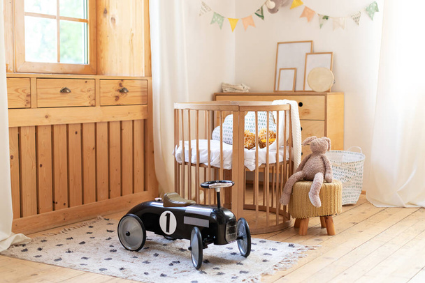 Çocuk odasının modern iç mekanı. Uzayı kopyala Hygge. Anaokulu. Sıcak İskandinav ışıkları bebek odası: yatak ve pelüş oyuncakları olan ahşap beşik. Çocuk odasında Retro tarzı oyuncak yarış arabası - Fotoğraf, Görsel