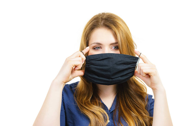 Woman using black protective reusable face mask, covering mouth. Coronavirus prevention. Health and safety. - Photo, Image