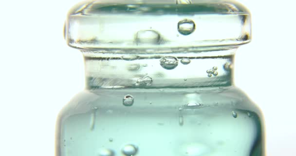 Detailní záběr modré bubliny sérum v lahvičce lékařského skla, izolované na bílém pozadí, přírodní esenciální olej, kosmetické, medicína. - Záběry, video