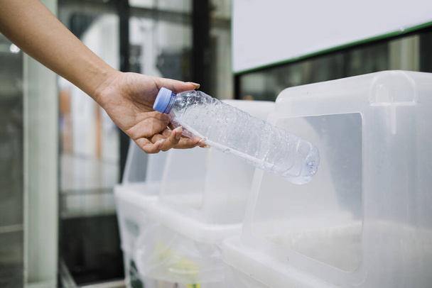 Χέρια που ρίχνουν χρησιμοποιημένες καθαρές πλαστικές φιάλες στα σκουπίδια. - Φωτογραφία, εικόνα