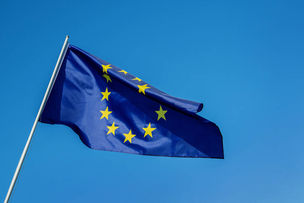 Σημαία της Ευρωπαϊκής Ένωσης κυματίζει στον άνεμο πάνω από τον γαλάζιο ουρανό - Φωτογραφία, εικόνα