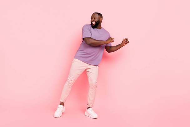 Photo of sweet adorable guy wear purple t-shirt dancing smiling isolated pink color background - Fotó, kép