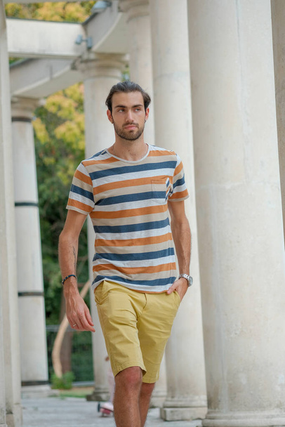 beautiful boy strolls in bermuda shorts and striped shirt. High quality photo - Foto, imagen