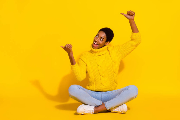 Portrait of attractive trendy cheerful girl sitting demonstrating copy blank space solution isolated on bright yellow color background - Foto, Imagen