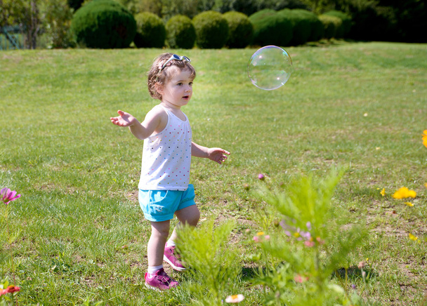 A little girl playing with soap bubbles - Photo, Image
