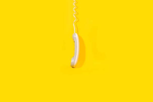 Ein digitaler Telefonhörer hängt auf gelbem Hintergrund mit Kopierraum - Foto, Bild