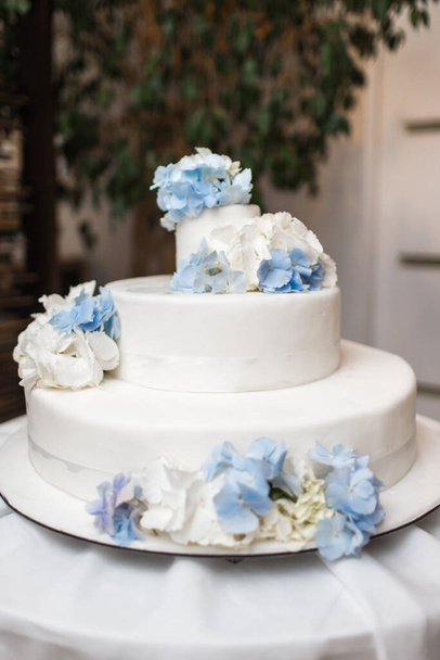 White wedding cake with blue flowers on a table - Fotografie, Obrázek
