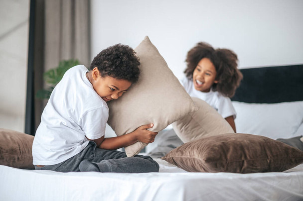 Siblings spending time at home and playing with pillows - Fotografie, Obrázek