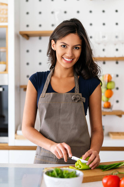 Beautiful happy young woman cooking at home. Healthy food, people concept - Foto, imagen