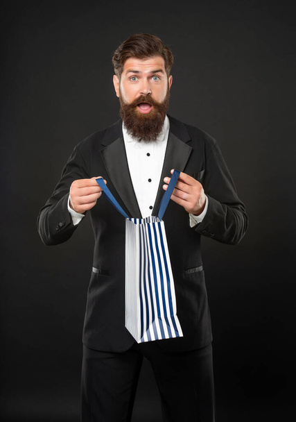 amazed man in tuxedo bow tie formalwear on black background with shopping bag. valentines day - Foto, imagen