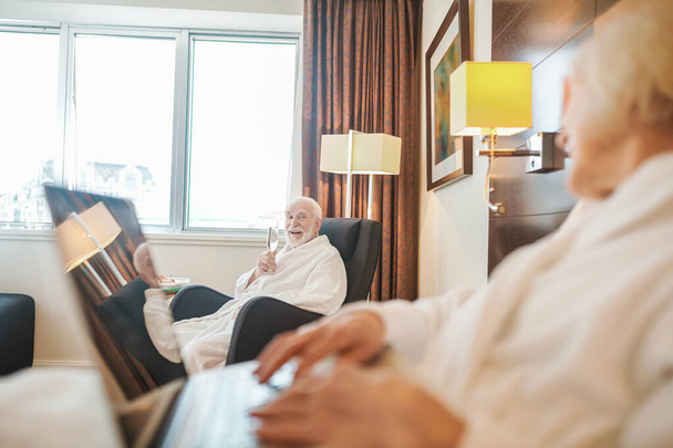 Elderly woman in a hotel room with a laptop - Fotoğraf, Görsel