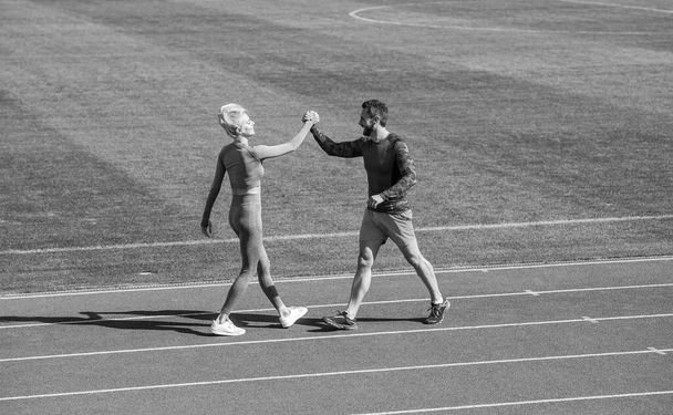 sport couple fitness partners celebrate team win with gesture of shake hand after exercising or compete in armwrestling on stadium running track arena outdoor, sport success - Photo, image
