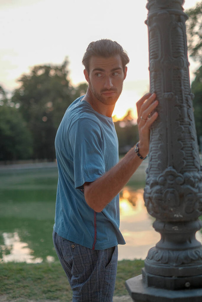 handsome Italian dark-haired boy leaning against the pole of the Ducal park in Parma. High quality photo - Fotó, kép