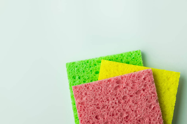 top view of pink, yellow and green sponge cloths on grey background - Fotó, kép