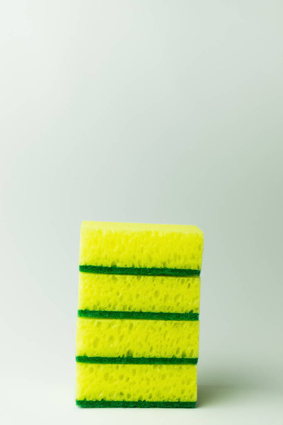 stack of porous yellow and green sponge scourers on grey background - Foto, Imagen